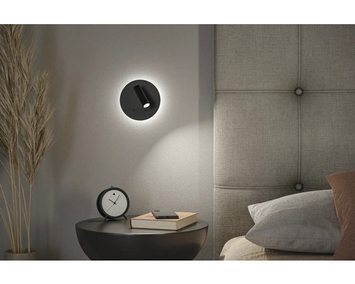 Schlafzimmer-Szene mit einem runden LED-Wandspot über einem Nachttisch mit Dekoration