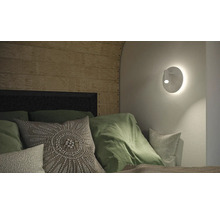 Schlafzimmer mit Wandleuchte, Kissen und Holzpaneelen