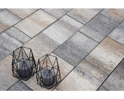 Verlegung von Pflastersteinen mit zwei dekorativen Windlichtern