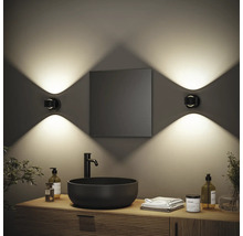 Modernes Badezimmer mit Waschbecken, Spiegel und zwei Wandleuchten für stimmungsvolle Beleuchtung