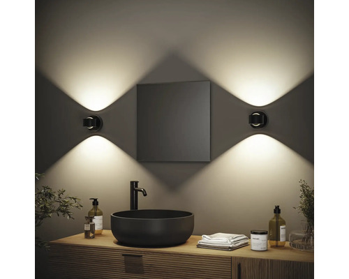 Modernes Badezimmer mit Waschbecken, Spiegel und zwei Wandleuchten für stimmungsvolle Beleuchtung