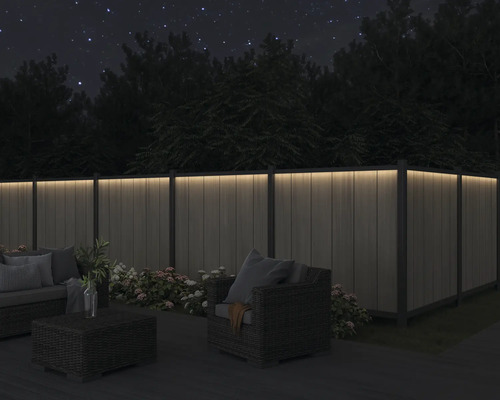 Terrasse mit beleuchtetem Zaun und Sitzgruppe bei Nacht