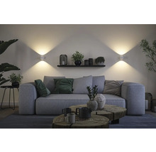 Wohnzimmer mit grauer Couch, Holztischen und Wandleuchten