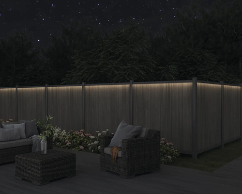 Nachts beleuchteter Garten mit Holzzaun und Gartenmöbeln