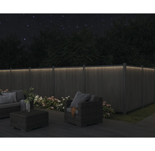 Beleuchteter Gartenzaun mit Gartenmöbeln bei Nacht