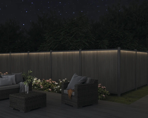 Beleuchteter Gartenzaun mit Gartenmöbeln bei Nacht