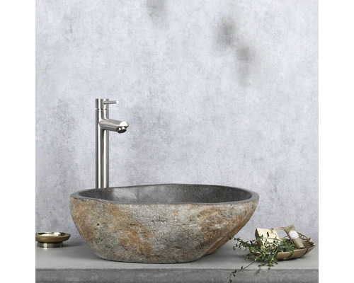 Naturstein-Waschbecken mit Armatur auf Ablage mit Seifenschale und Dekoration