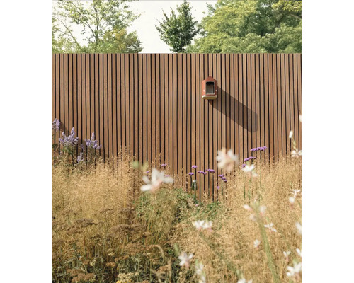 Holzzaun mit Vogelhaus und Gartenpflanzen