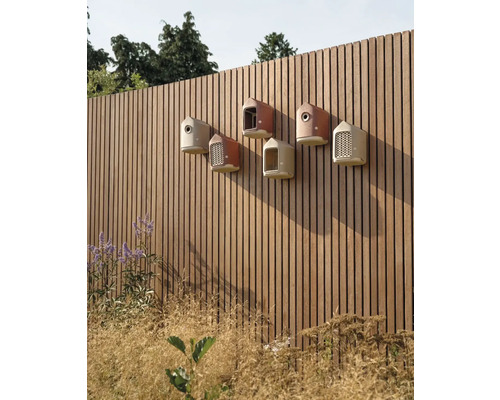 Eine Reihe von Vogelhäusern an einem Holzzaun in einem Garten