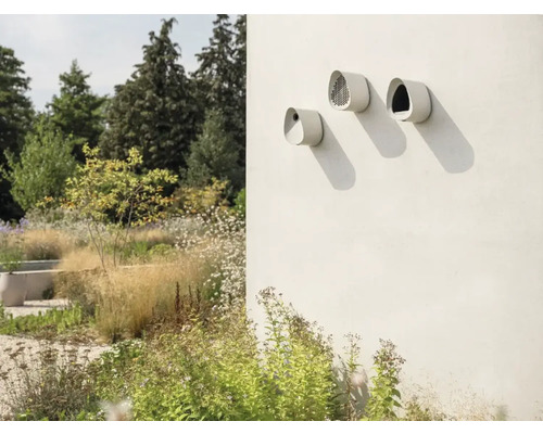 Drei Nistkästen an einer Wand in einem Garten.