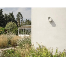 Außenansicht eines Gartens mit einem Gewächshaus und einer an der Wand montierten Außenleuchte