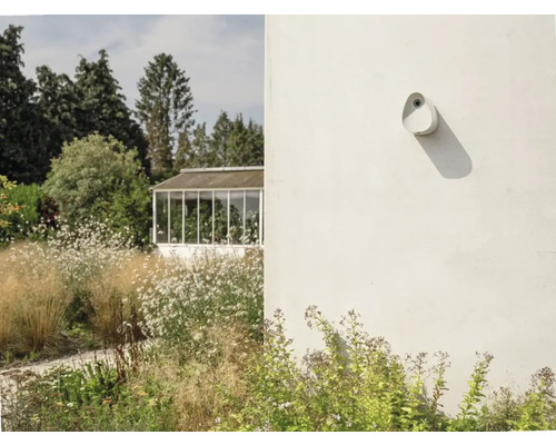 Außenansicht eines Gartens mit einem Gewächshaus und einer an der Wand montierten Außenleuchte