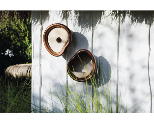 Zwei dekorative Pflanzgefäße an einer Holzwand im Freien.