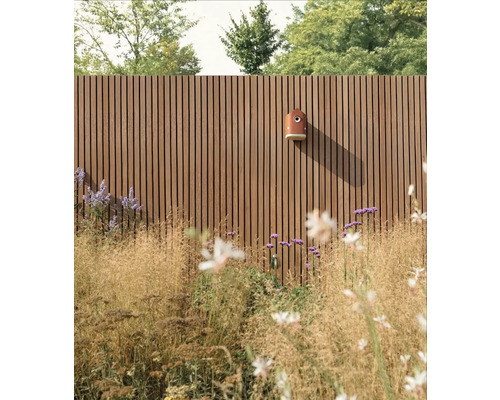 Holzzaun mit montiertem Vogelhaus und Bepflanzung