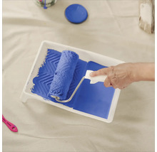 Farbe wird mit Farbroller in einer Farbwanne aufgenommen.