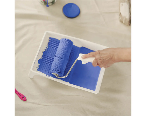 Farbe wird mit Farbroller in einer Farbwanne aufgenommen.
