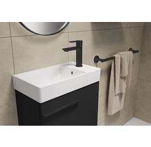 Waschtisch mit schwarzem Unterschrank, Armatur, Handtuchhalter und Handtuch in einem Badezimmer.