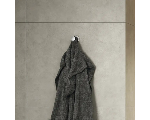 Grauer Bademantel hängt an einem Wandhaken im Badezimmer.