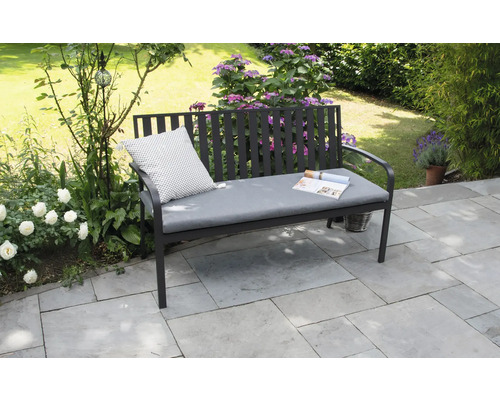 Gartenbank mit Kissen und Zeitschrift im Garten