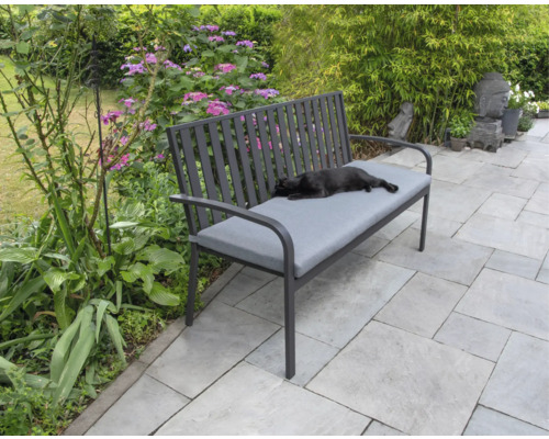 Gartenbank mit grauer Auflage und liegender Katze im Garten.