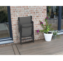 Zusammengeklappter Gartenstuhl neben einem Blumentopf auf einer Terrasse