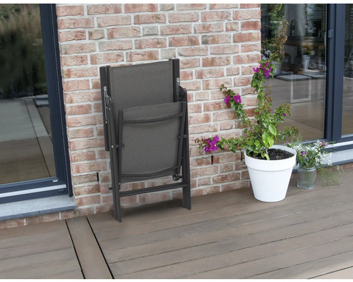 Zusammengeklappter Gartenstuhl neben einem Blumentopf auf einer Terrasse