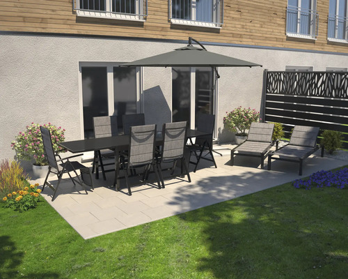 Gartenszene mit Esstisch, Stühlen, Sonnenschirm und Sonnenliegen auf einer Terrasse