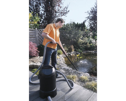 Mann reinigt Gartenteich mit Teichschlammsauger.