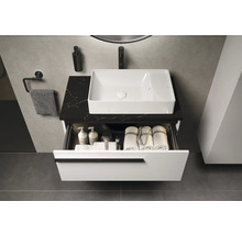 Badezimmer mit Waschbecken, Waschtisch mit Schublade, Handtüchern und Badutensilien.