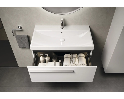 Badezimmer Waschbeckenunterschrank mit geöffneter Schublade, darin Handtücher und Badutensilien.