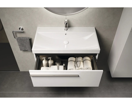 Waschtisch mit offenem Schubfach, Handtüchern und Badutensilien im Badezimmer.
