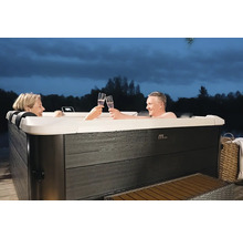 Ein Paar stößt in einem Whirlpool im Freien mit Sekt an