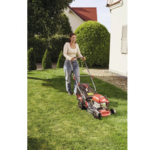 Frau bedient Rasenmäher im Garten.