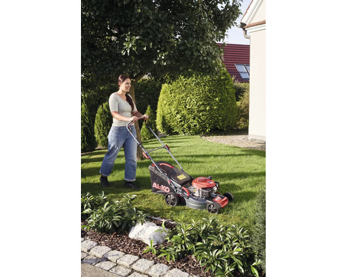 Frau mäht Rasen mit Rasenmäher von AL-KO im Garten.