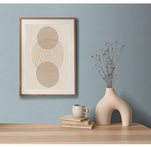 Dekoratives Stillleben mit gerahmtem Kunstdruck, Büchern, Tasse und Vase auf einem Tisch