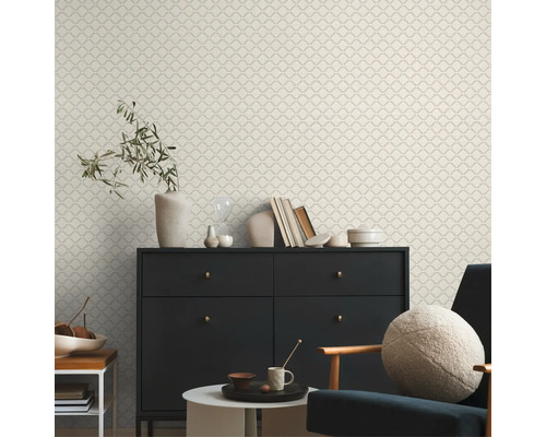 Wohnraum mit gemusterter Tapete, Kommode, Sessel und Dekoration