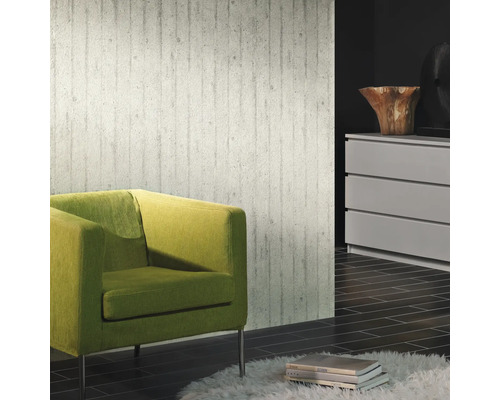 Wohnraum mit Betonoptik Tapete, grünem Sessel und Kommode