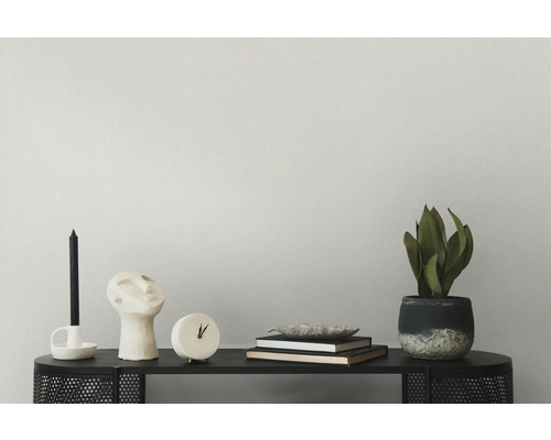 Dekorative Elemente auf einem schwarzen Tisch, darunter eine Kerze, eine Büste, eine Uhr, Bücher und eine Topfpflanze.