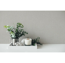 Dekorative Stillleben-Szene mit strukturiertem Hintergrund, bestehend aus Kerze, Ornament und Pflanze.