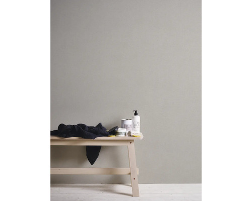 Wand mit Kosmetikprodukten und einem Tuch auf einem Holzbänkchen