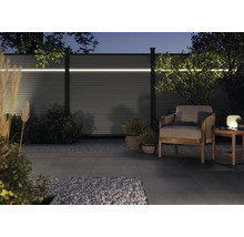 Garten mit beleuchtetem Sichtschutzzaun, Sessel und Tischlampe bei Nacht