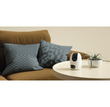 Imou Überwachungskamera auf einem Tisch neben einer Zimmerpflanze und einem Sofa