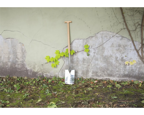 Spaten mit Holzgriff an einer Wand