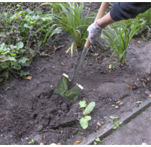 Person benutzt einen Spaten zum Umgraben im Garten.