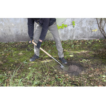 Eine Person gräbt mit einem Spaten ein Loch im Garten.