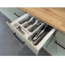 Geöffnete Küchenschublade mit Besteckeinsatz und verschiedenen Besteckteilen.