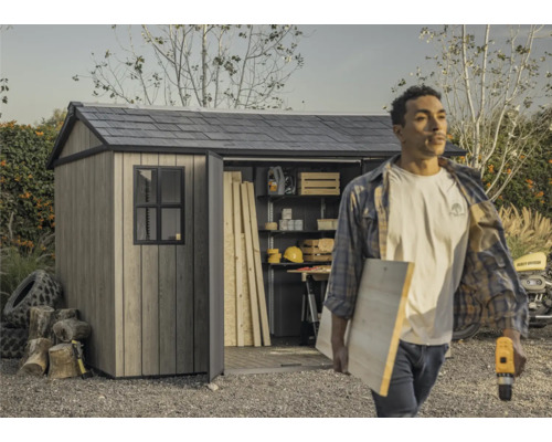 Gartenschuppen mit offenstehender Tür und einer Person, die Werkzeuge und Holz trägt