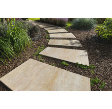 Gartenszene mit rechteckigen Trittplatten aus Stein, die einen Weg durch einen mit Rindenmulch bedeckten Garten bilden