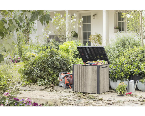 Garten im Freien mit Aufbewahrungsbox, Schlauchaufroller, Gießkanne und Pflanzen