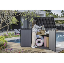 Aufnahme einer Frau, die eine Aufbewahrungsbox im Außenbereich auf einer Holzterrasse neben einem Pool benutzt, um Gegenstände zu verstauen